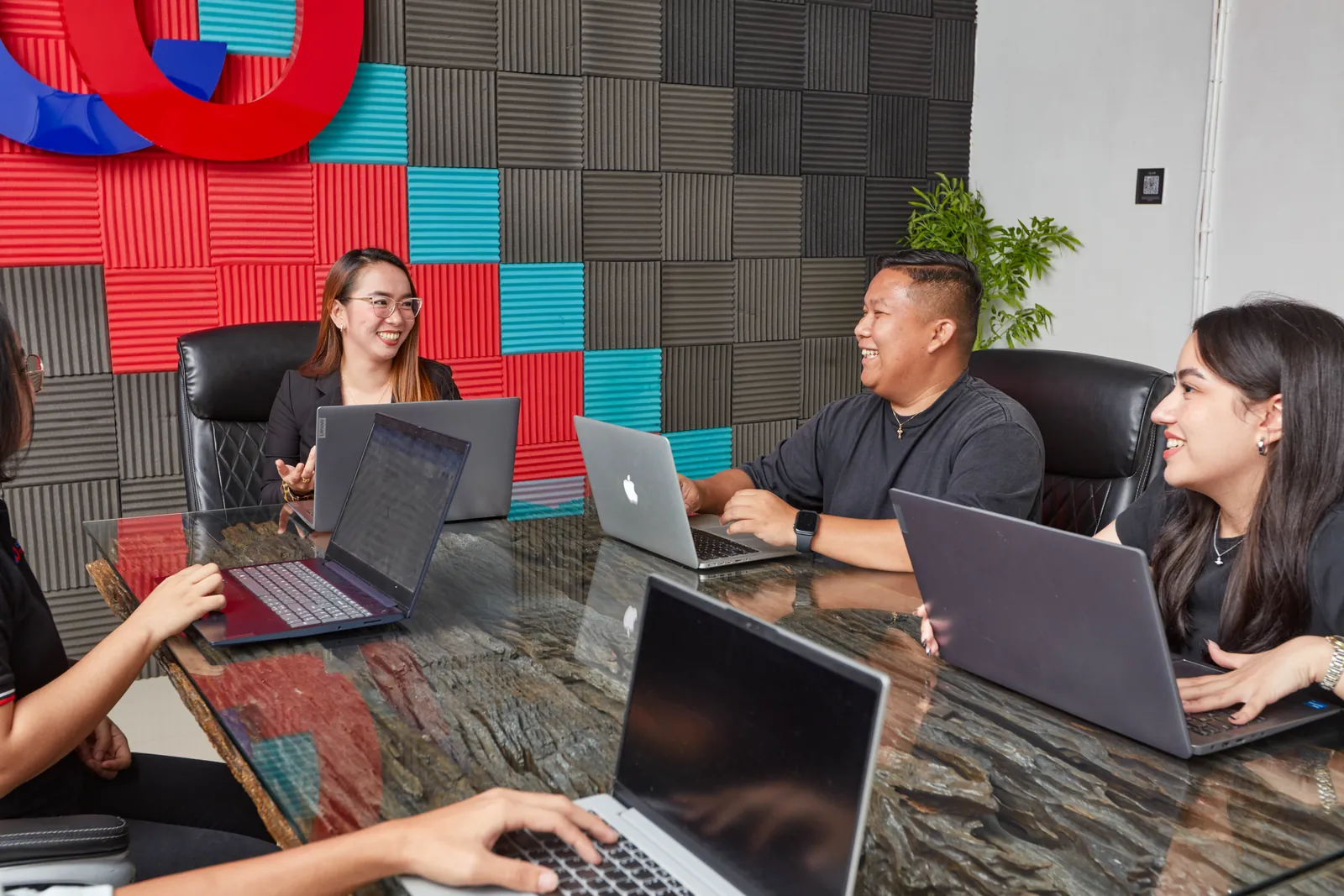 Colleagues collaborating with laptops around a meeting table in the Philippines office