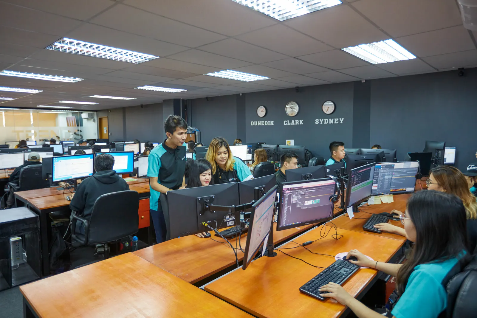 Colleagues discussing work at computer stations in our Philippines outsourcing office