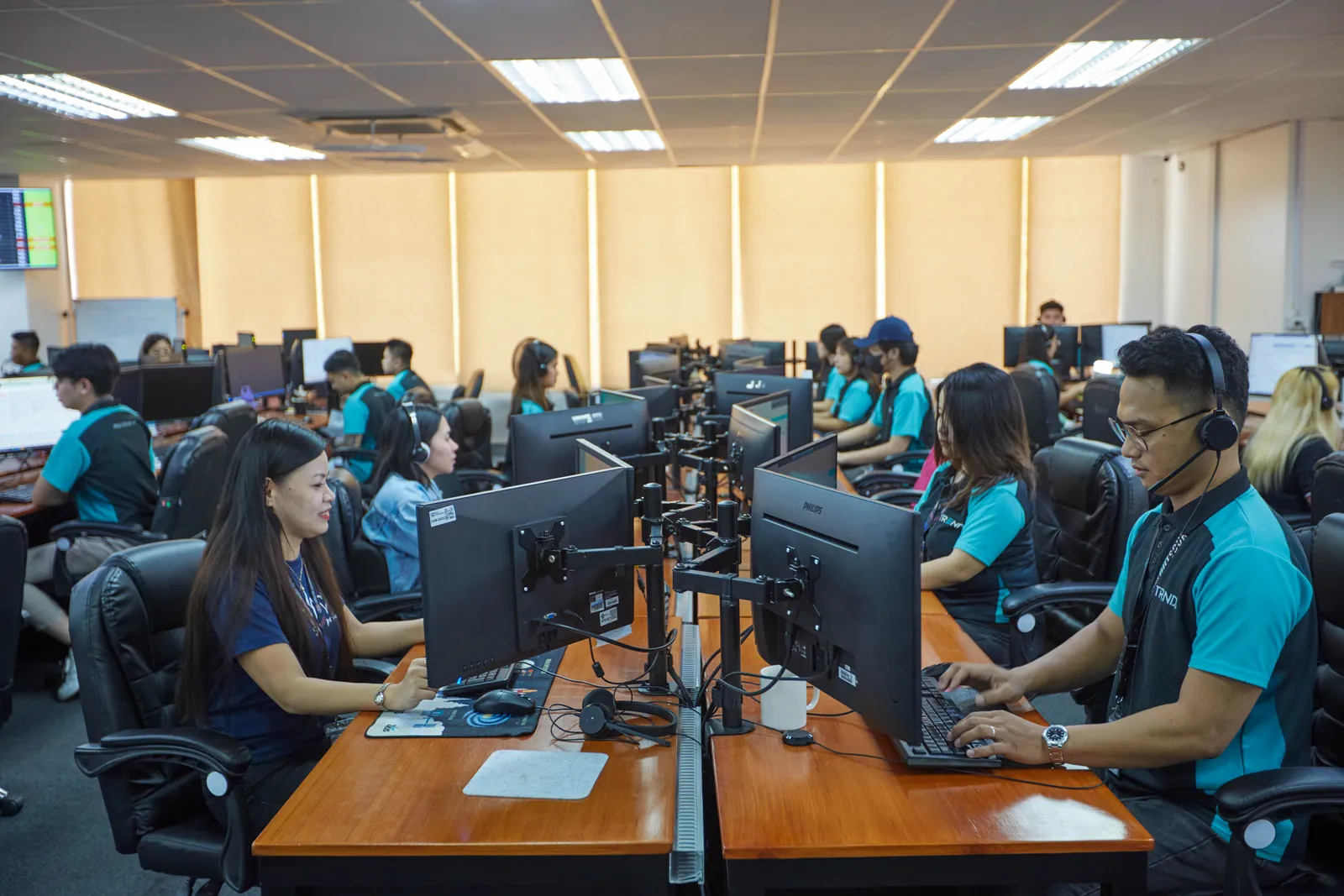 Team members using desktop computers and headsets in the Philippines outsourcing office
