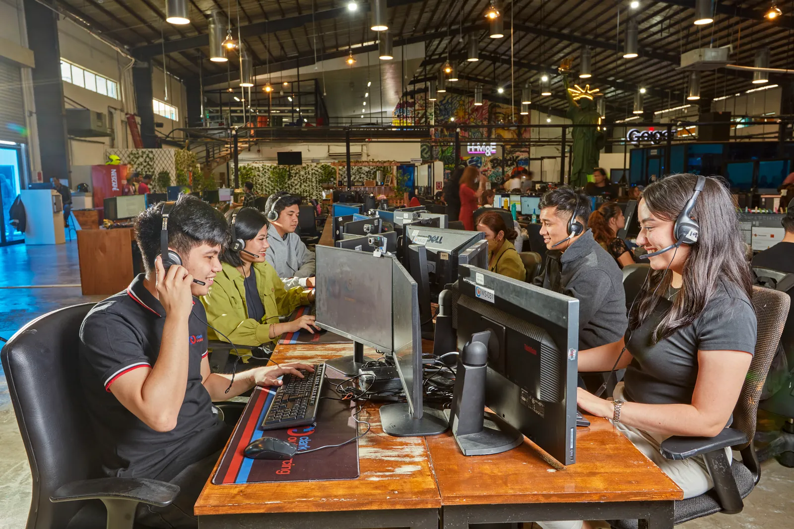 Staff using a phone and headsets at shared workstations in the Clark, Philippines office