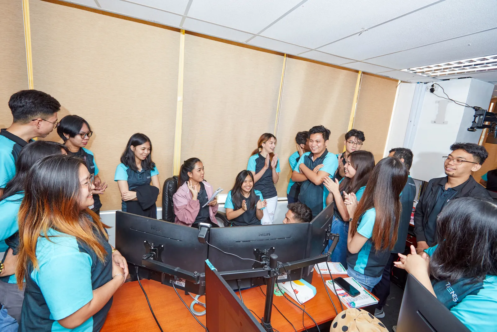 Colleagues discussing work together around computer stations in the Philippines office